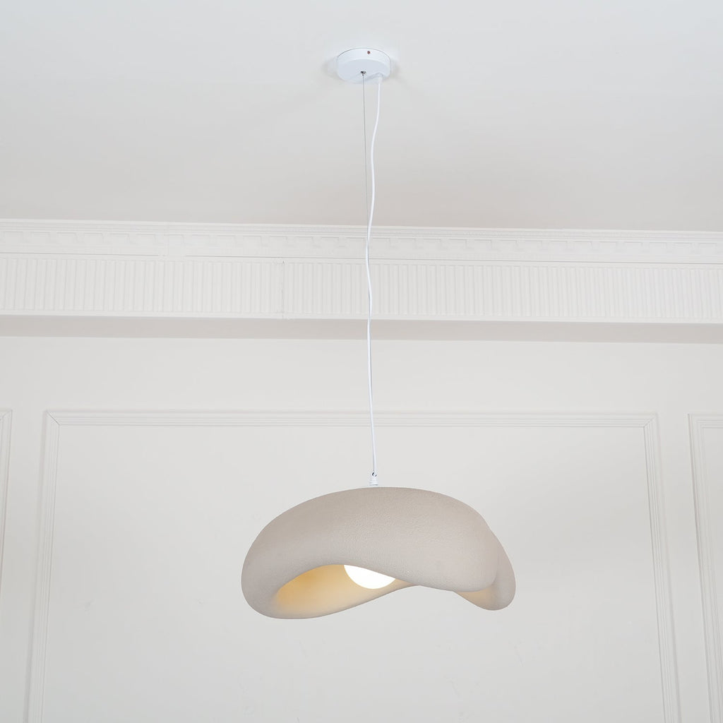 Beige Clérachic pendant on a white cord from a round white ceiling canopy, small in a tall panelled white room.