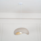Beige Clérachic pendant on a white cord from a round white ceiling canopy, small in a tall panelled white room.