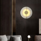 Clérachic round alabaster wall lamp lighting a dark panelled bedroom wall above the bedside table.