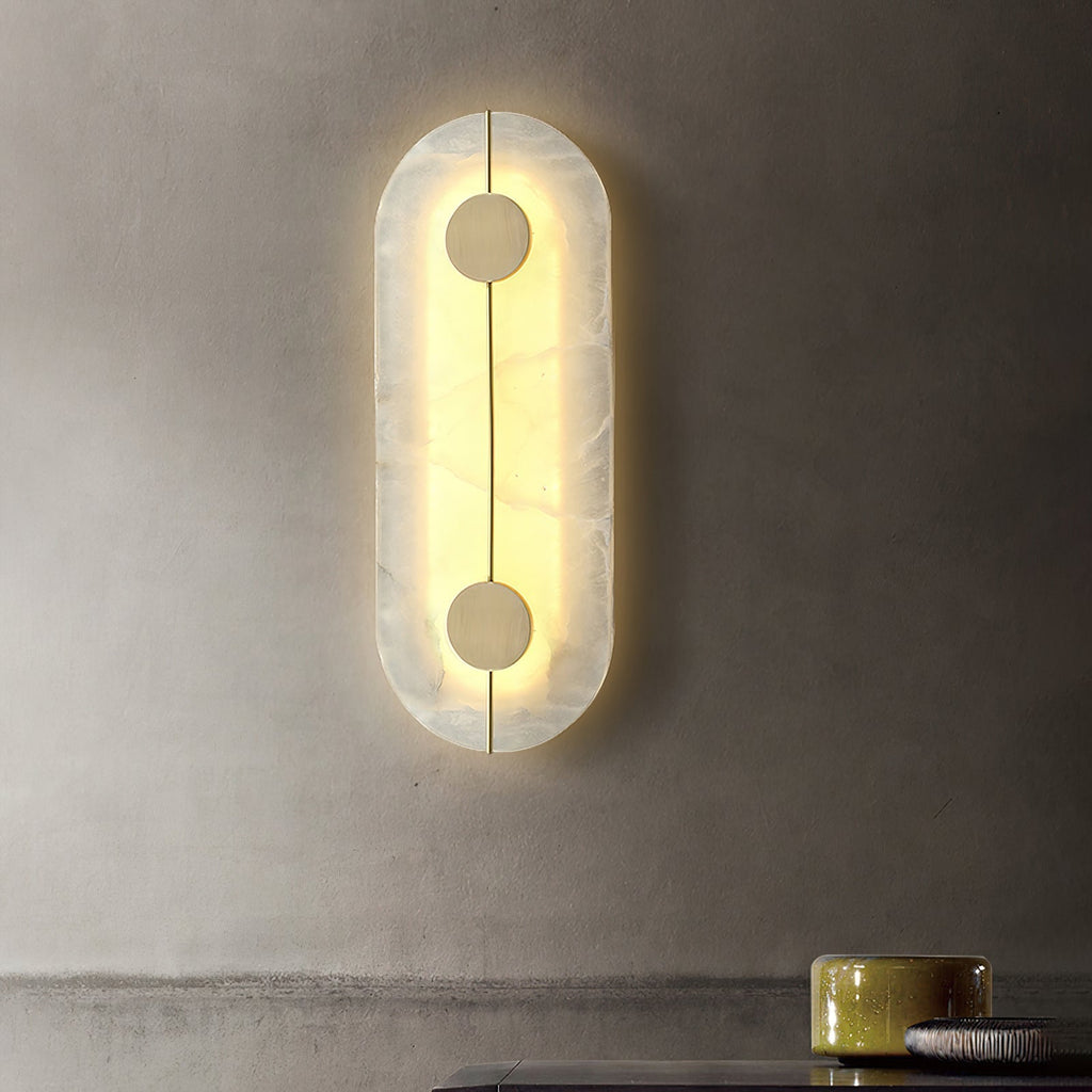 The Clérachic tall wall lamp glowing on a limewashed plaster wall above a counter set with ceramic bowls.
