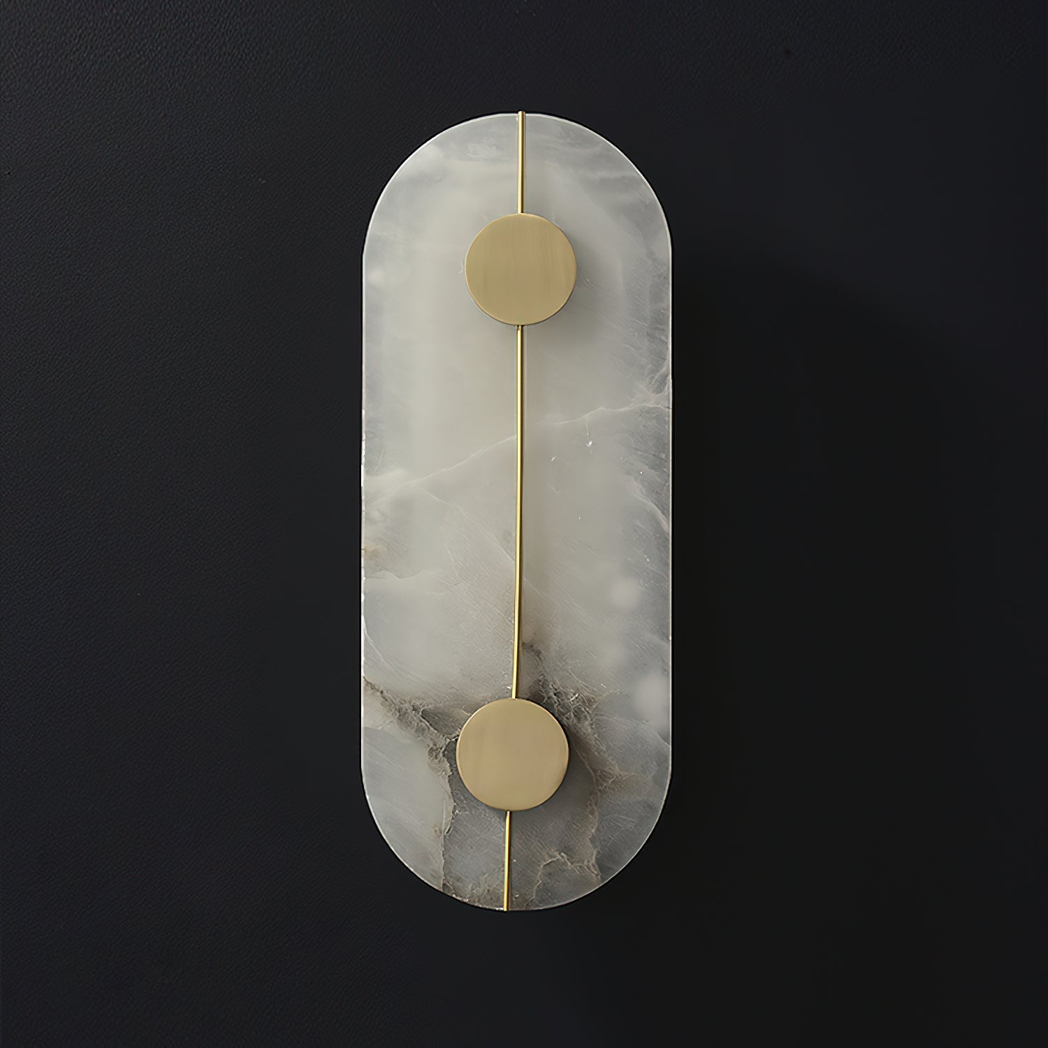 The Clérachic tall capsule wall lamp unlit on a dark wall, grey veining marbling the alabaster slab.