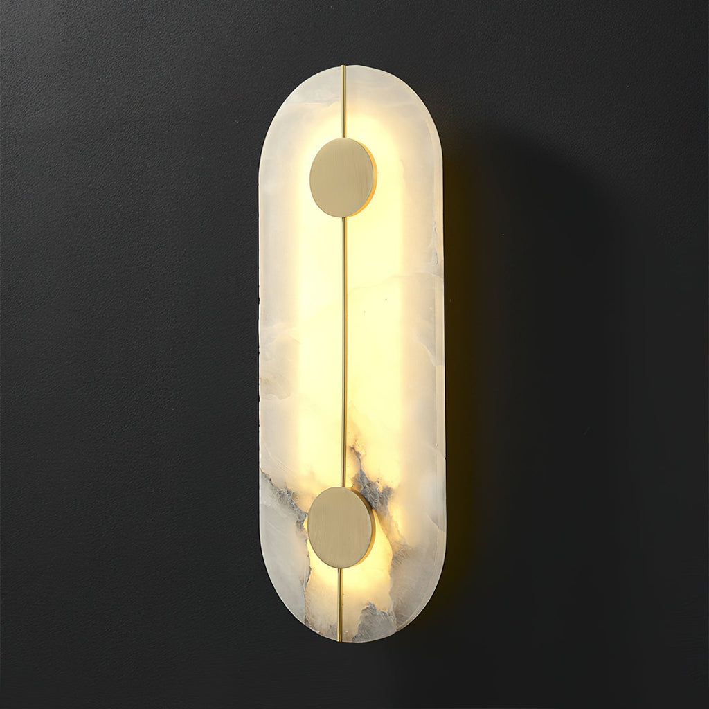 The Clérachic tall wall lamp lit against charcoal, the alabaster edge glowing warm around the brass rod.