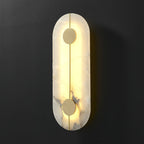The Clérachic tall wall lamp lit against charcoal, the alabaster edge glowing warm around the brass rod.