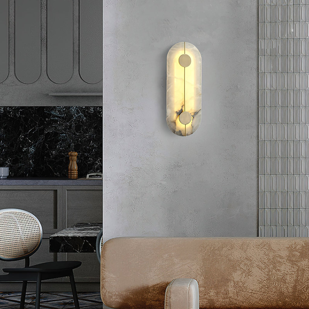 The Clérachic tall alabaster sconce lit on a plaster wall beside a tiled kitchen splashback and dining chairs.