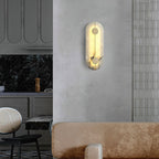 The Clérachic tall alabaster sconce lit on a plaster wall beside a tiled kitchen splashback and dining chairs.