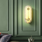 Clérachic tall wall lamp glowing against deep green panelling, the alabaster warm above a cushioned sofa.