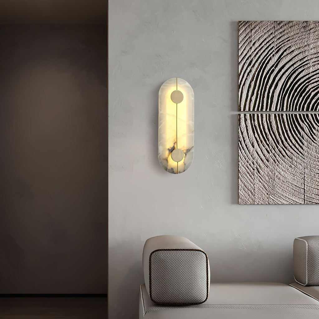 Clérachic tall wall lamp lit on a pale wall beside carved wood panels, warm light washing the alabaster.