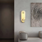 Clérachic tall wall lamp lit on a pale wall beside carved wood panels, warm light washing the alabaster.