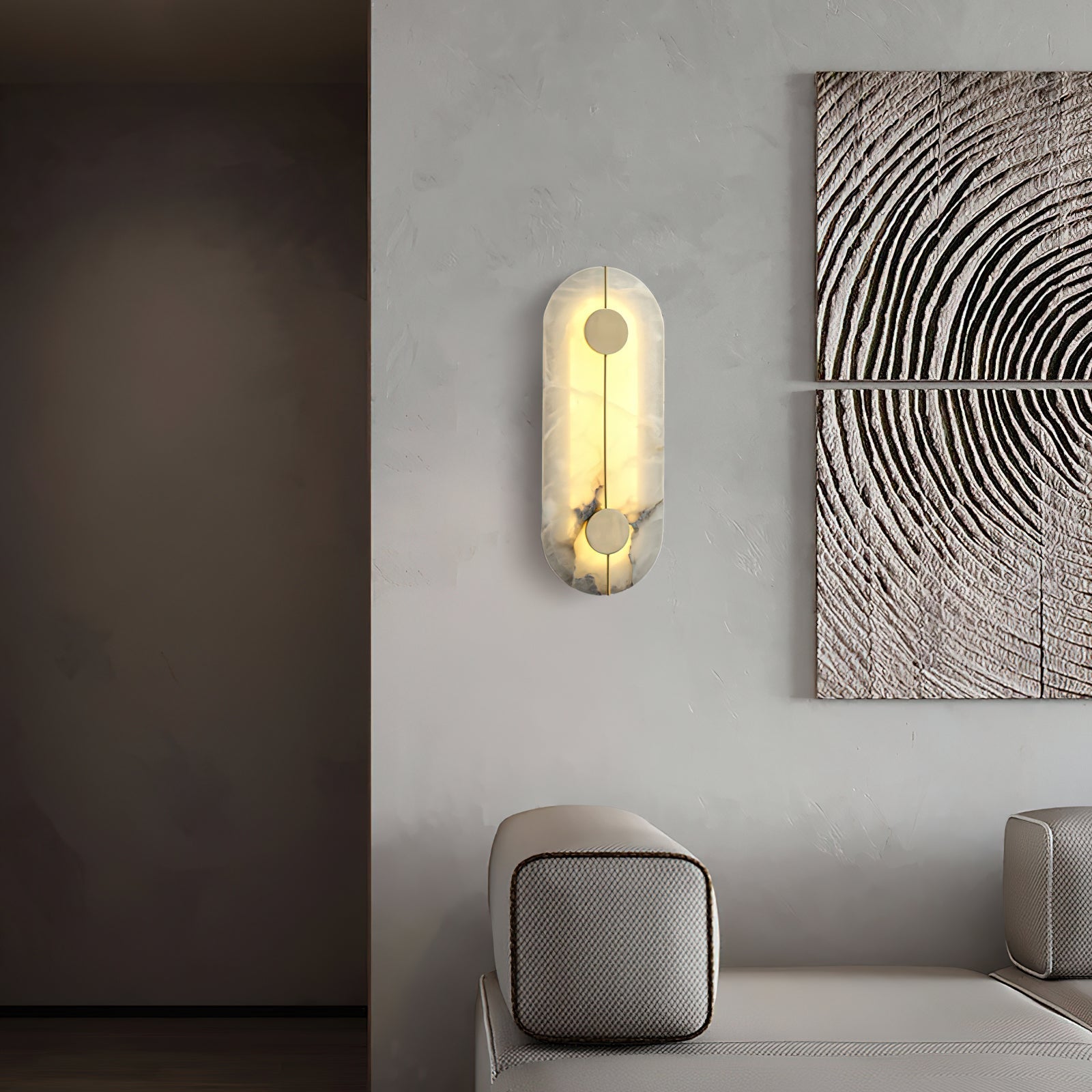 Clérachic tall wall lamp lit on a pale wall beside carved wood panels, warm light washing the alabaster.