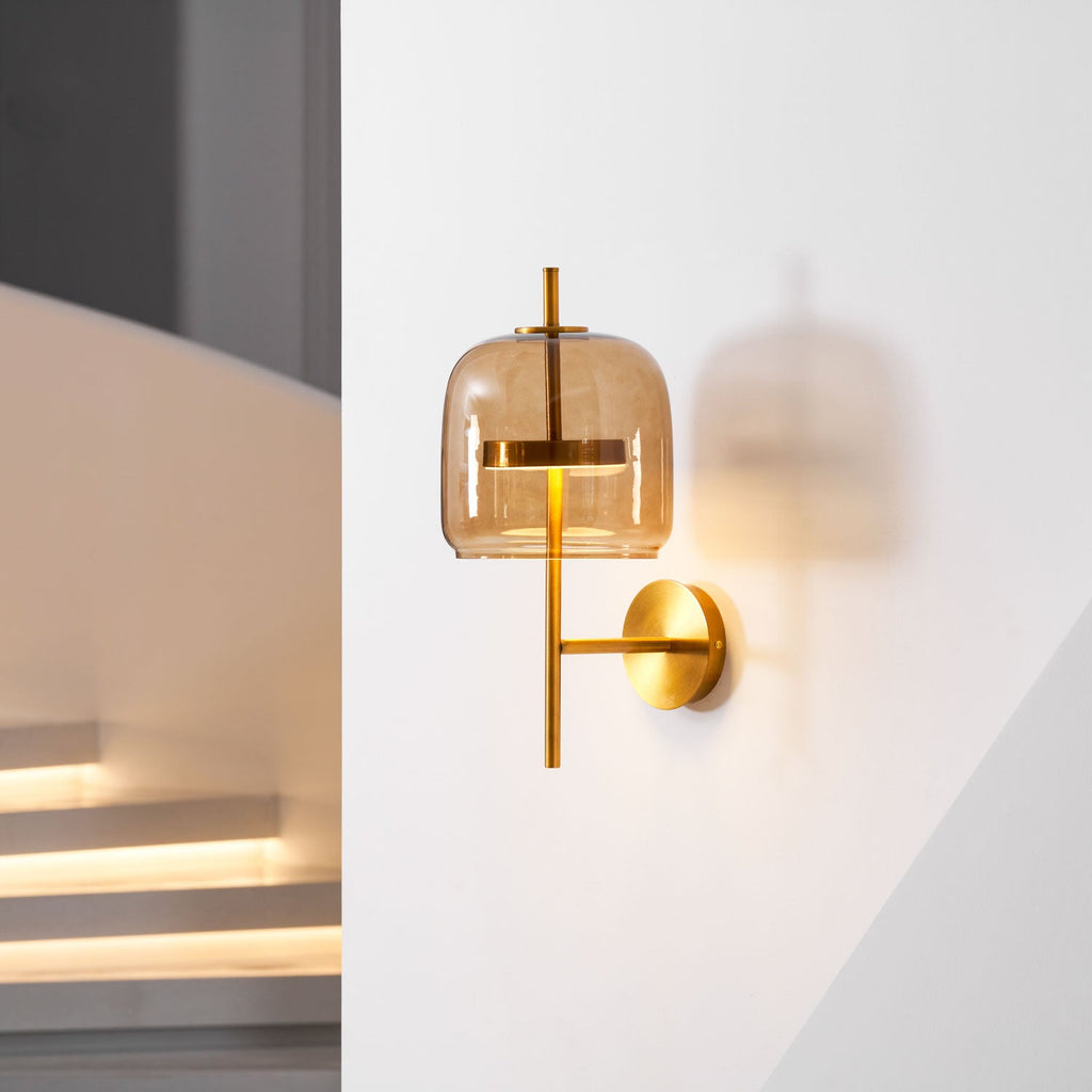 This Clérachic wall light, with a coffee glass shade and gold arm, glows beside a pale staircase wall with lit steps below.