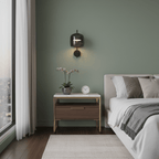 This Clérachic wall light, in black with a smoke grey glass shade, hangs on a sage-green wall above a bedside table with an orchid.