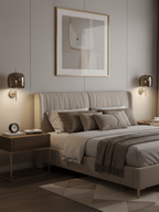 Gold-framed Clérachic wall lights with smoke grey shades flank a quilted bed under a framed abstract print.