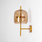 Coffee-tinted glass shade, gold ring and slim gold stem on this Clérachic wall light, shown unlit on a white wall.