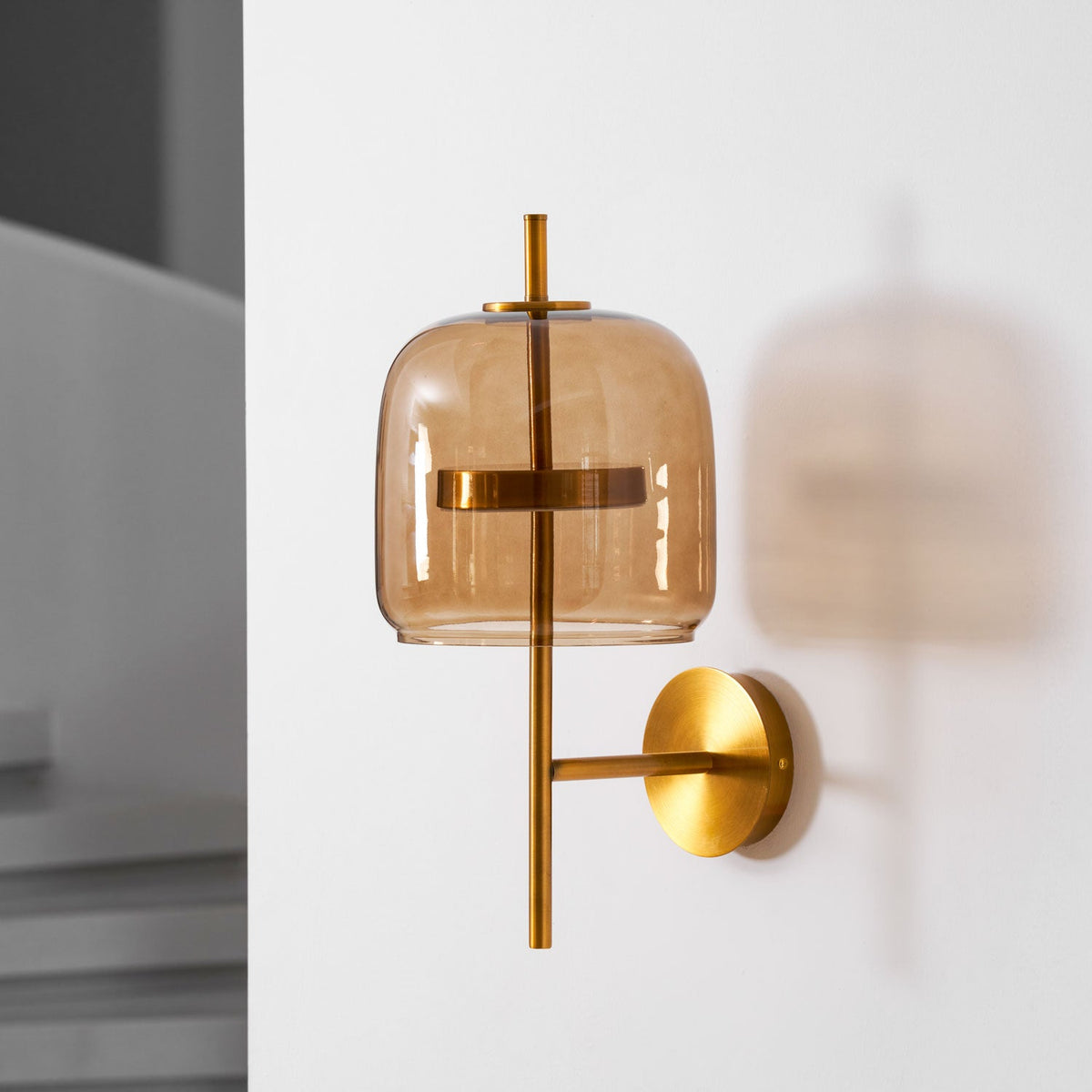 Unlit Gold & Coffee Clérachic wall light on a white wall, with a soft shadow behind the shade and a grey interior at the edge.