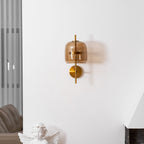 Closer view of this Clérachic wall light on a white wall above a cherub statue, with its coffee glass shade and gold stem.