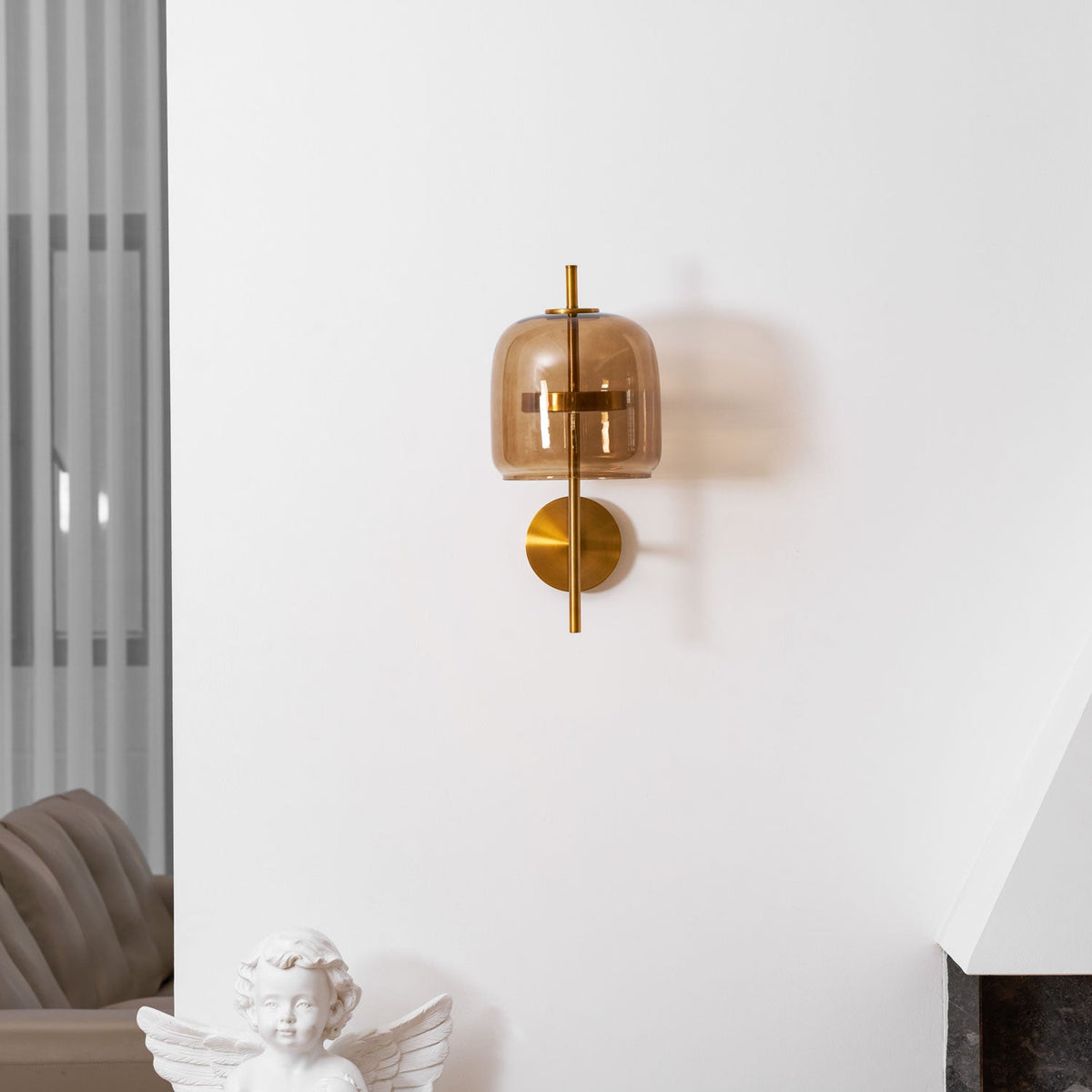 Closer view of this Clérachic wall light on a white wall above a cherub statue, with its coffee glass shade and gold stem.