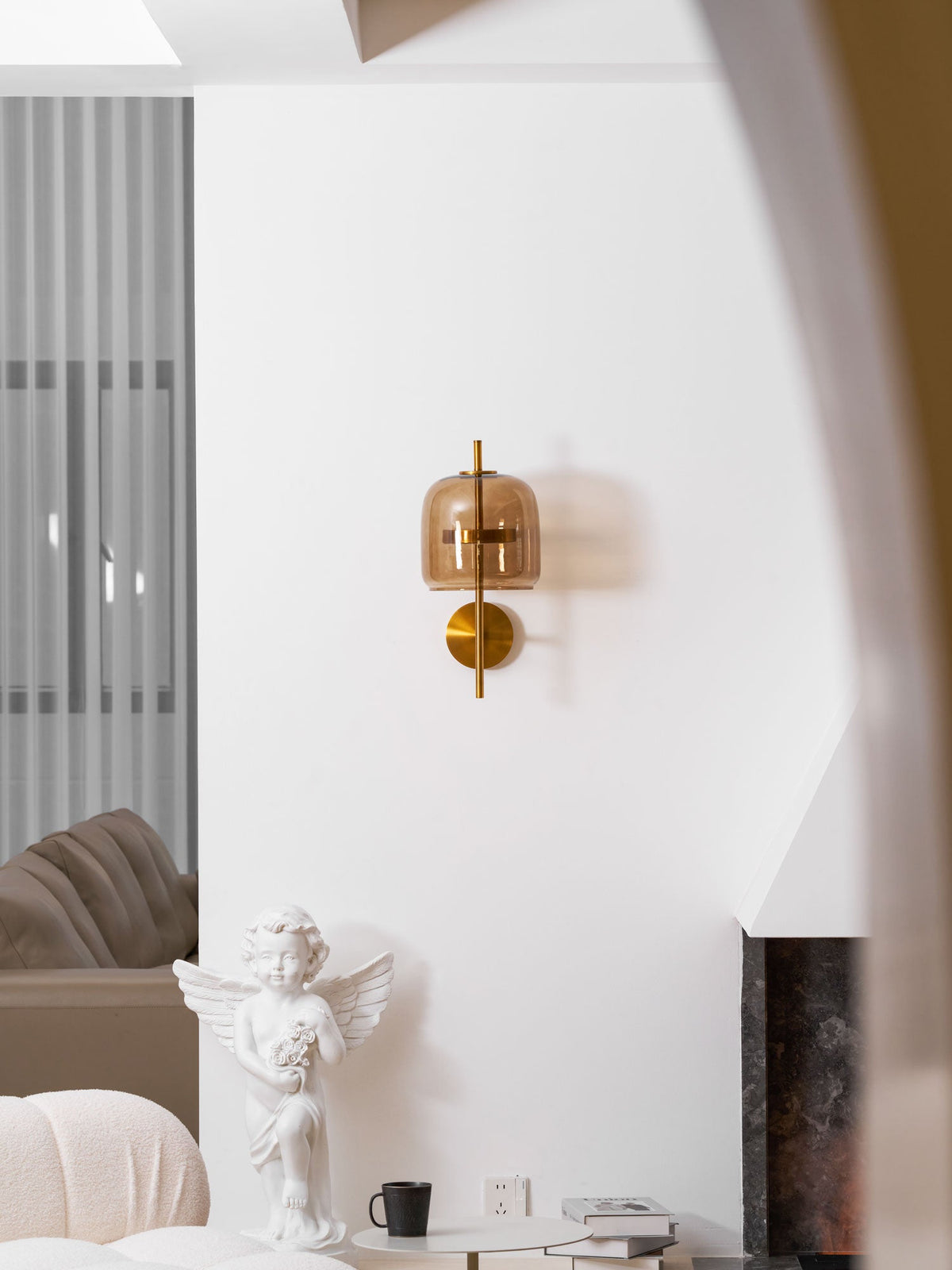 This Clérachic wall light in gold and coffee glass, seen from further back on a white wall by an arched opening and a cherub statue.