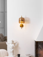 A lit Clérachic wall light with a coffee shade high on a white wall, seen above a cherub statue and a dark stone fireplace.