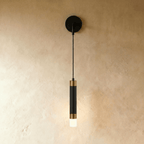 Clérachic wall light with a black backplate and cord, a black cylinder capped in brass-toned bands and a frosted tip.