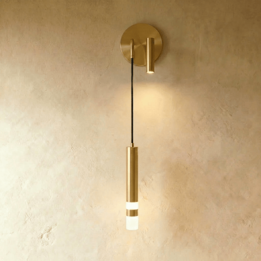 Clérachic brass-toned wall light with a round backplate, a small adjustable spotlight and a hanging cylinder with a frosted tip.