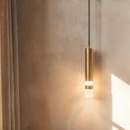 Clérachic brass-toned cylinder wall light with a frosted glass tip, glowing beside a linen curtain on a limewashed wall.