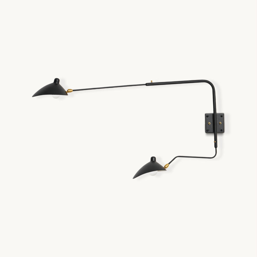 This Clérachic two-head wall light on a plain backdrop, with black curved arms ending in cone shades and brass joints, on a square wall plate.
