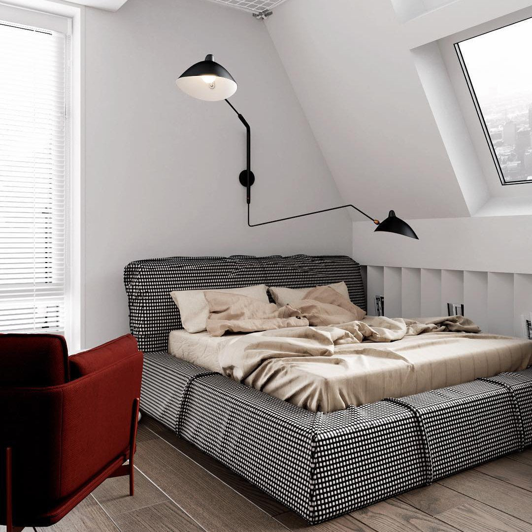 A Clérachic black wall light above a houndstooth bed in an attic bedroom, with one head angled upward and one out to the side.