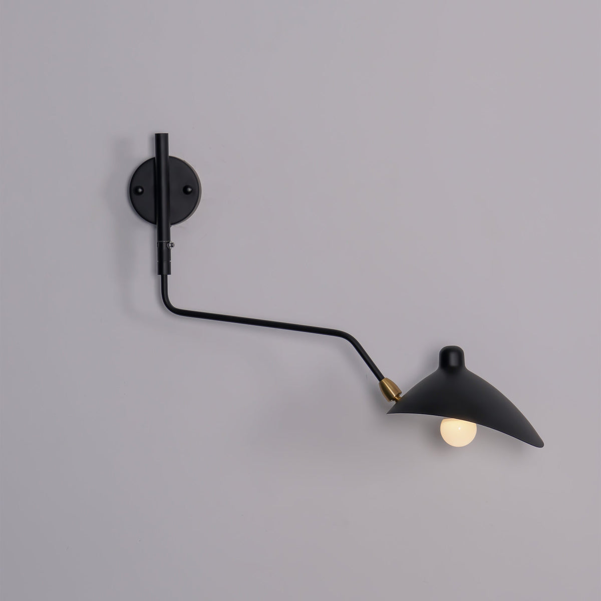 Clérachic black one-head wall light with a curved arm and a bare bulb, on a mauve-grey wall.