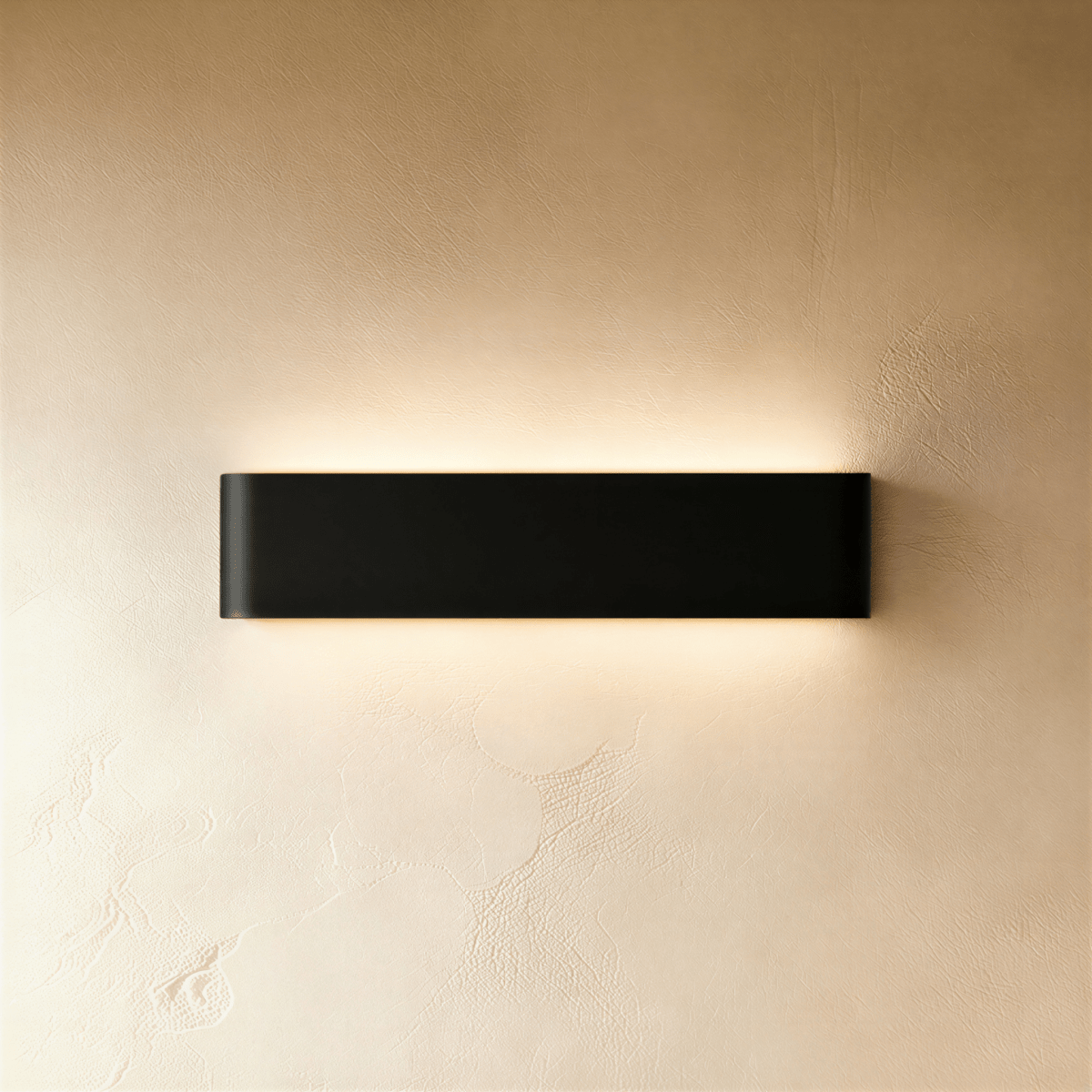 Clérachic black aluminium wall light, a medium length, casting a warm band of light up and down a textured plaster wall.