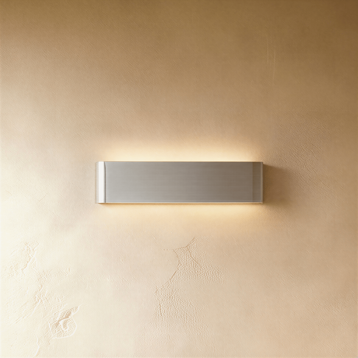 Clérachic slim brushed silver aluminium wall light with rounded ends, lit above and below against warm plaster.