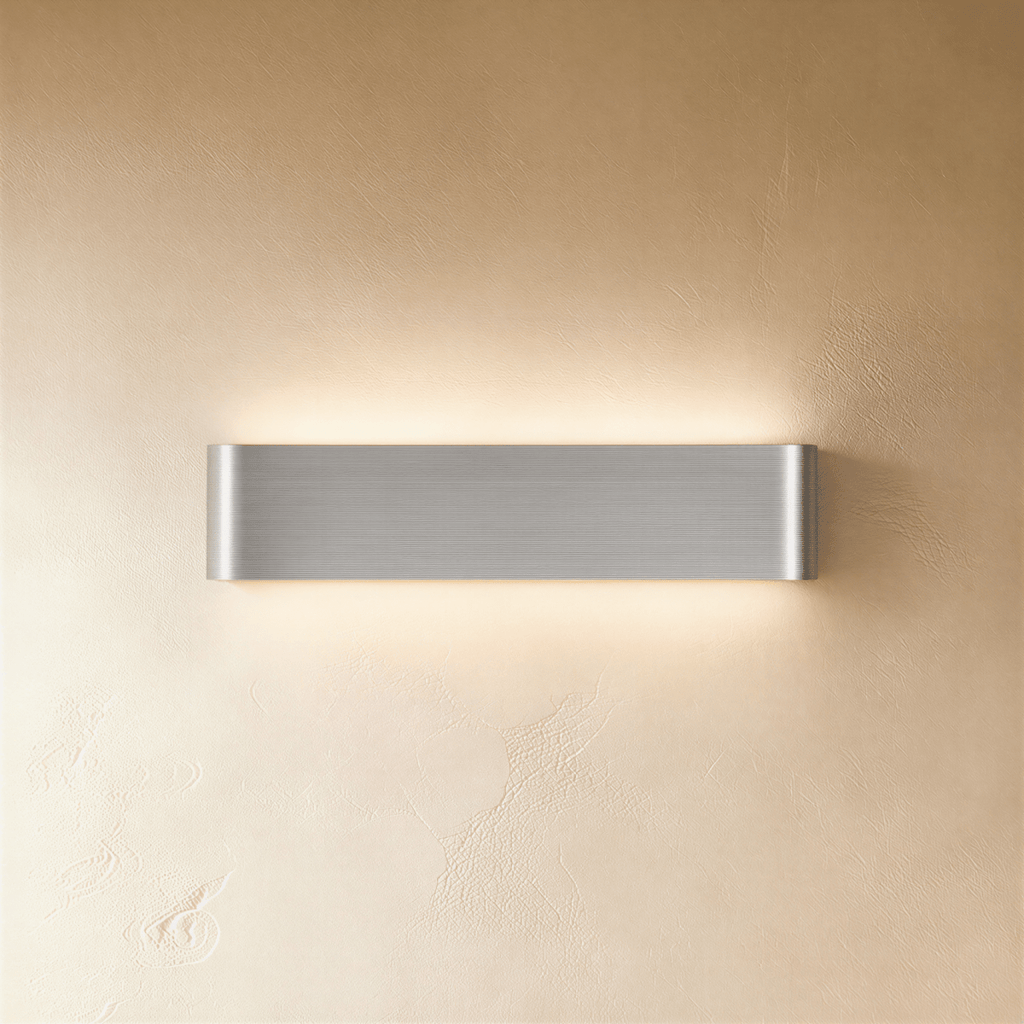 Clérachic brushed silver aluminium wall light in a medium length, its fine metal grain catching a soft warm glow.