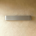 Clérachic long brushed silver aluminium wall light switched off, showing its fine horizontal grain on textured plaster.