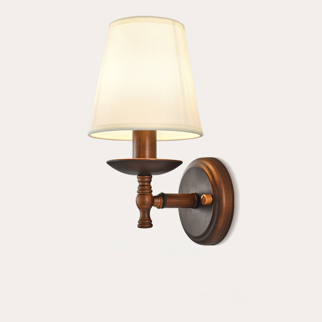 Large front view of the white fabric shade, brown dish and short turned arm of this Clérachic wall light, on a pale background.