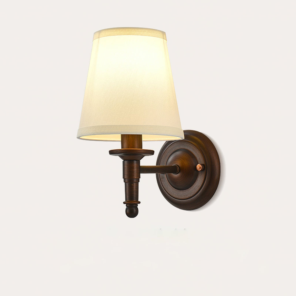 Close view of the Clérachic wall light with a straight, turned brown arm ending in a small ball, under a cream fabric shade.