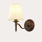 Larger view of the curved-arm Clérachic wall light, with its round antique brown backplate and a tapered cream shade, unlit.