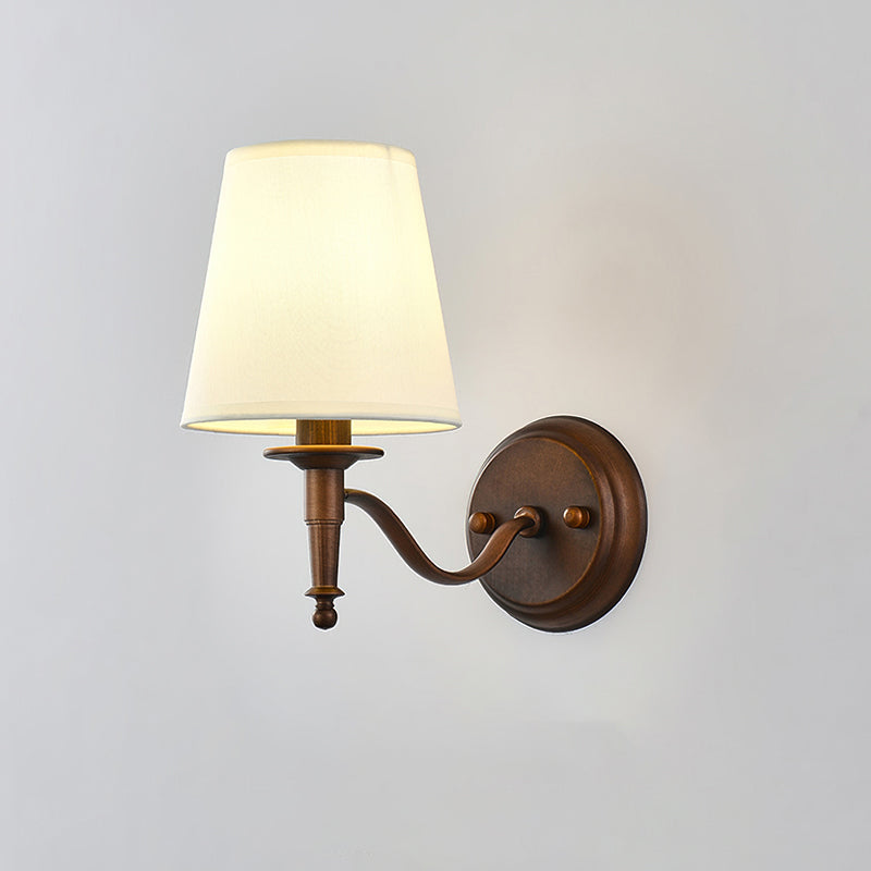 Clérachic wall light with a long S-shaped brown arm, its shade softly lit against a light grey wall.
