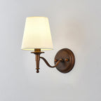 Clérachic wall light with a long S-shaped brown arm, its shade softly lit against a light grey wall.