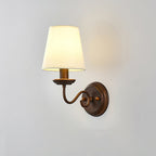 Side-on view of the swan-neck Clérachic wall light on a grey wall, with a soft glow behind the white shade and a round brown backplate.