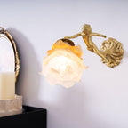 Closer view of the Clérachic cherub wall light, its frosted rose shade lit warm above a candle on a black cabinet.