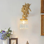 A Clérachic cherub wall light with a crystal drop shade, mounted high on a wall above a vase of purple flowers and gilt frames.
