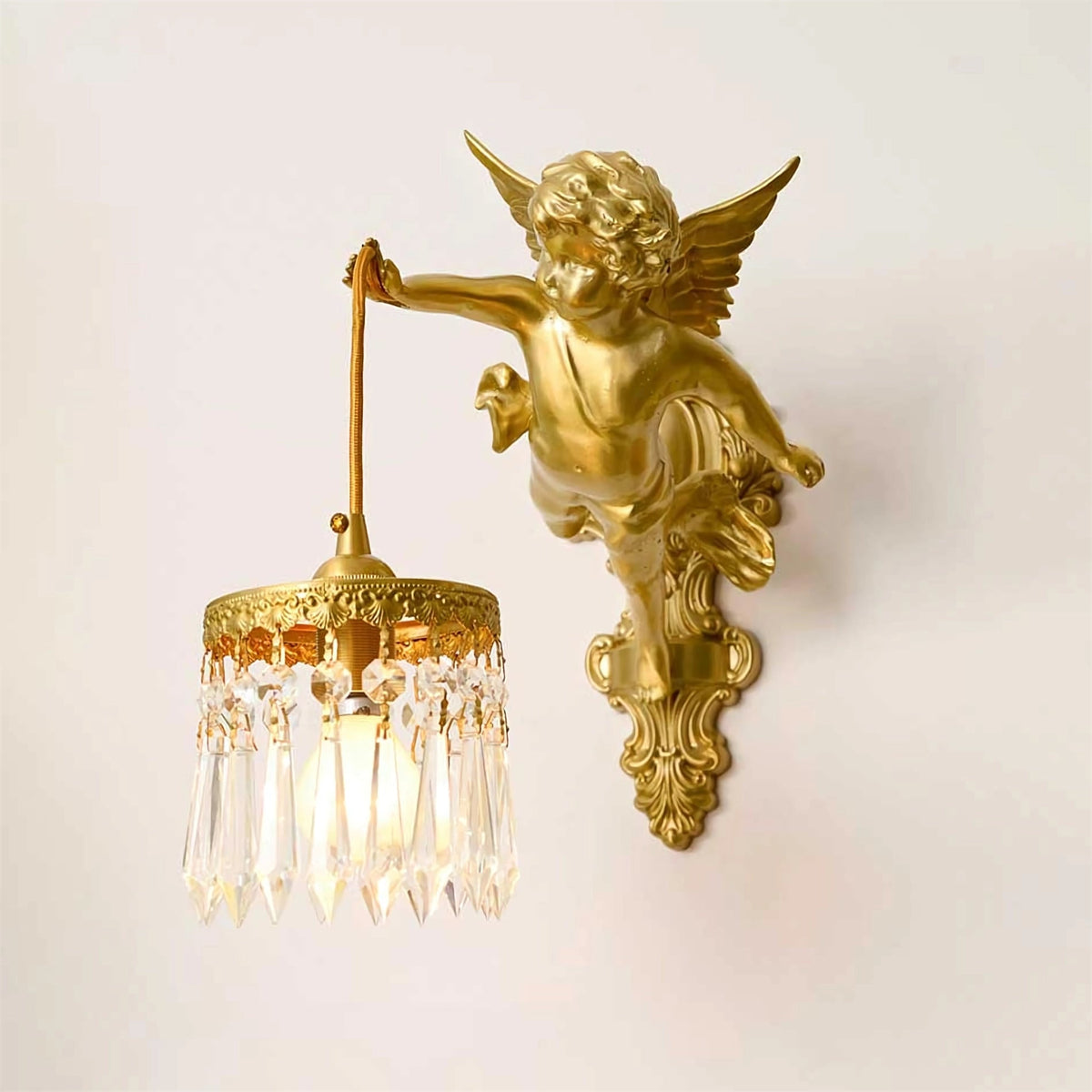 A cherub with outstretched wings holds the crystal-fringed shade of this Clérachic wall light, shown on a plain cream wall.
