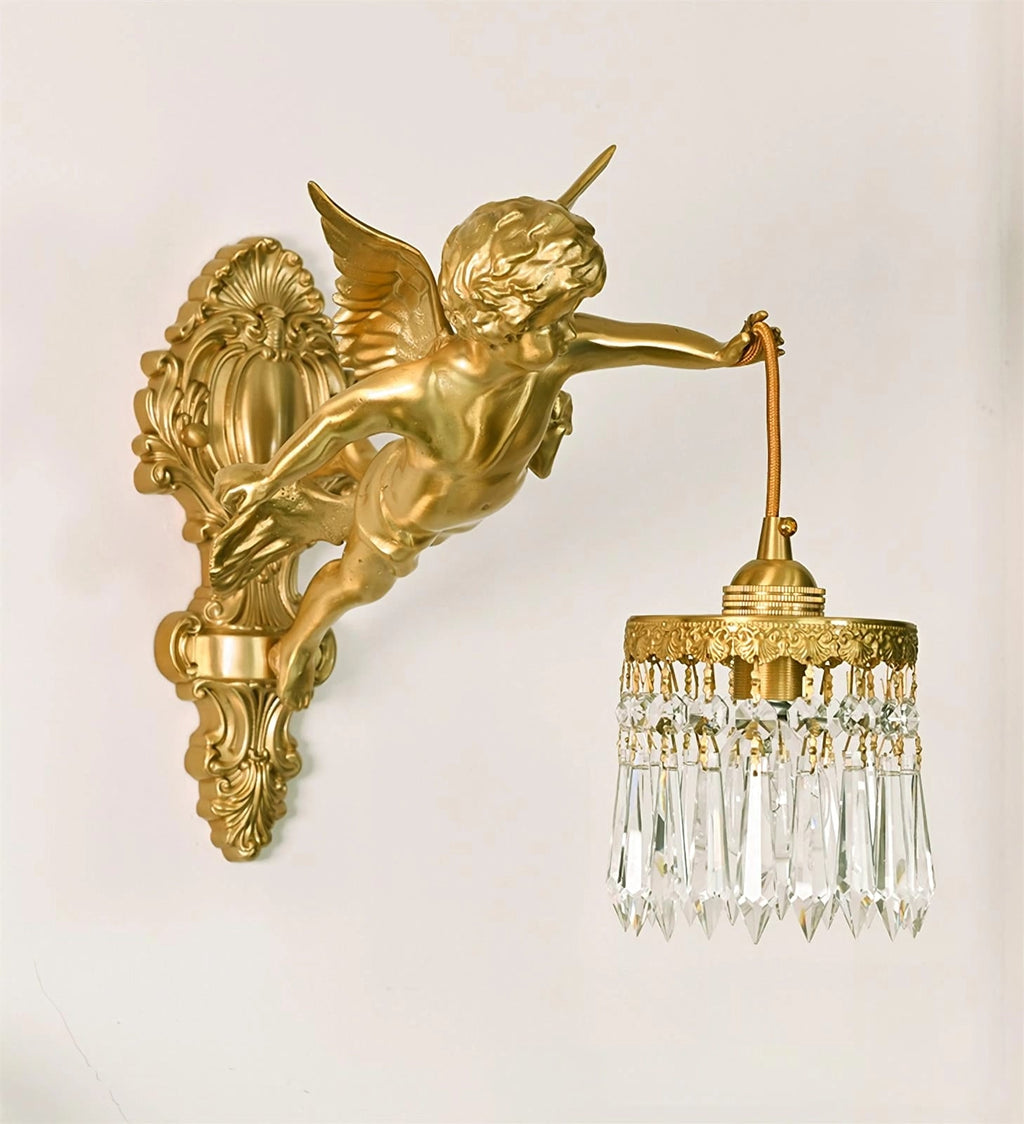 The cherub, brass back plate and crystal-fringed shade of this Clérachic wall light, shown against a cream wall.