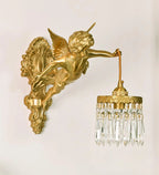 The cherub, brass back plate and crystal-fringed shade of this Clérachic wall light, shown against a cream wall.