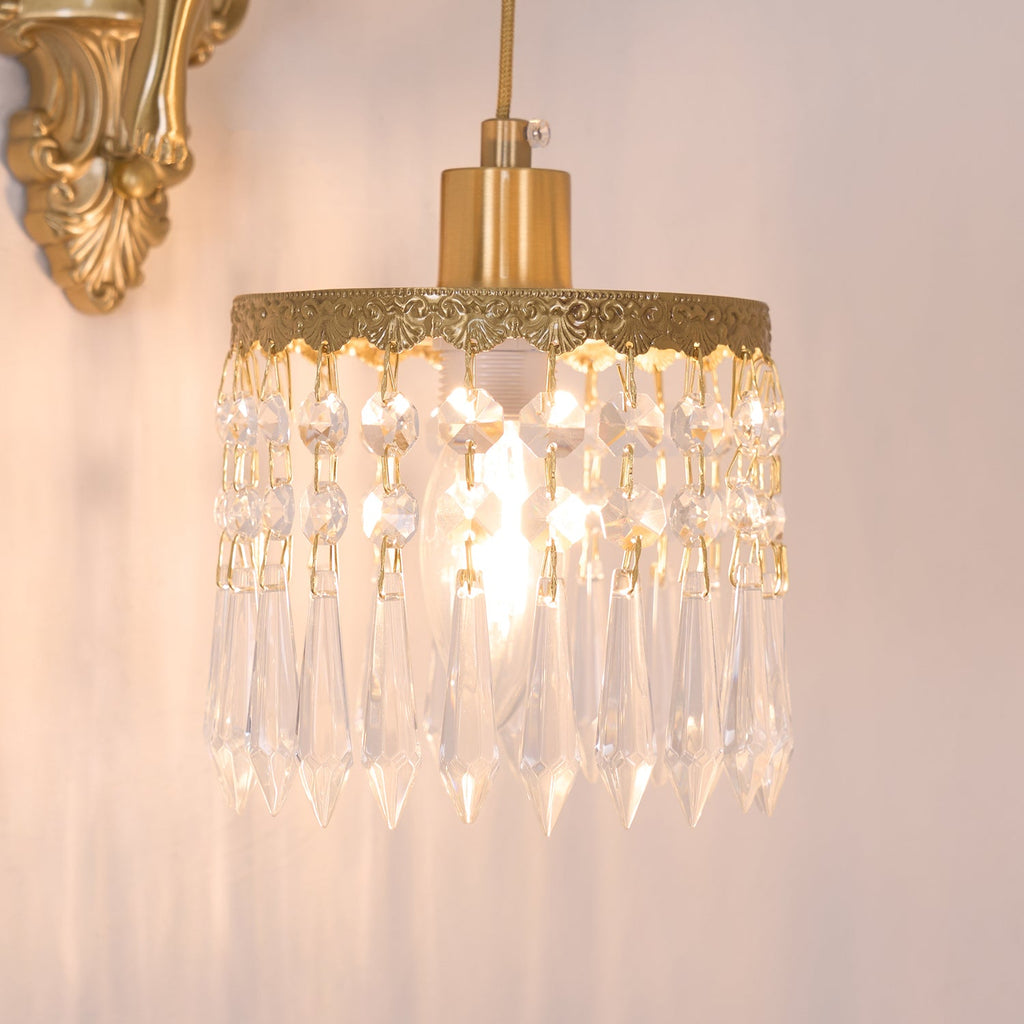 Close view of the lit crystal-fringed shade on this Clérachic wall light, with the glow spilling warm onto a pale wall.