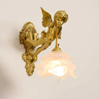 A Clérachic cherub wall light with a lit frosted rose shade and a long scrolled back plate, on a soft beige backdrop.