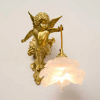 Front view of the cherub with spread wings on this Clérachic wall light, its rose shade glowing beneath on a beige backdrop.