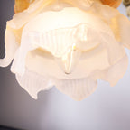 Close view of the ridged frosted glass petals of the rose shade on this Clérachic wall light, lit from within.