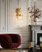 In a panelled white room with a red woven armchair and a grey fireplace, a Clérachic cherub wall light hangs above the seating.