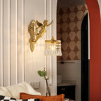 A Clérachic cherub wall light hangs on a panelled wall beside a red arch, with a cushioned sofa below it.