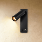 Clérachic matt black wall reading light glowing warm, with a USB socket at the base of its slim rectangular backplate.